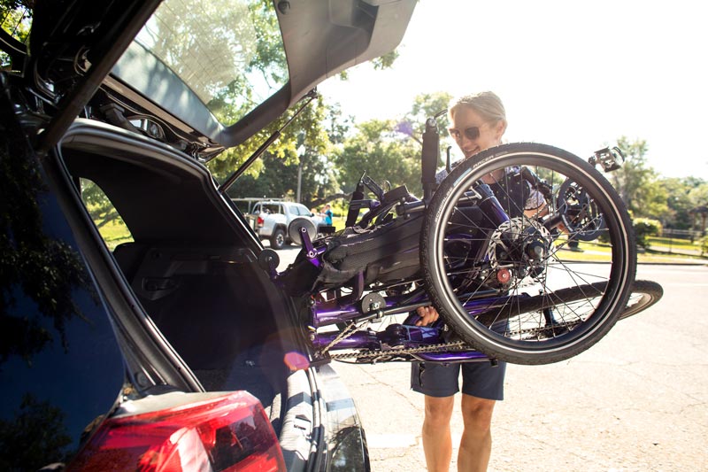 Cycling woman putting a folded Catrike into the back of her SUV