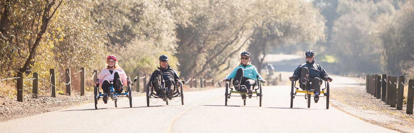 Group of recumbent trike riders going down the middle of a road