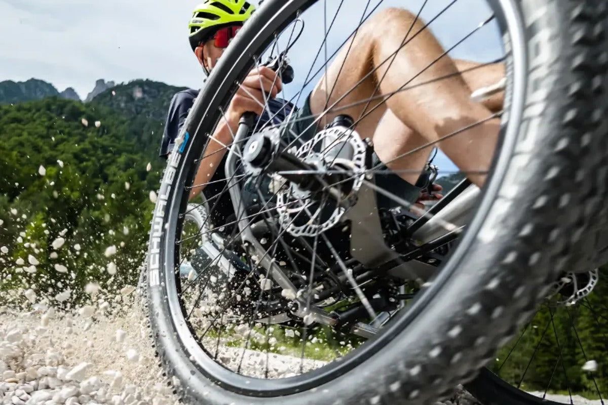 Rider on the AZUB Ti-FLY X kicking up gravel on a trail, showing its three big 26-inch off-road wheels