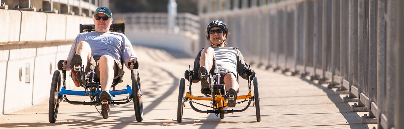 Two men riding Greenspeed recumbent trikes over the American River