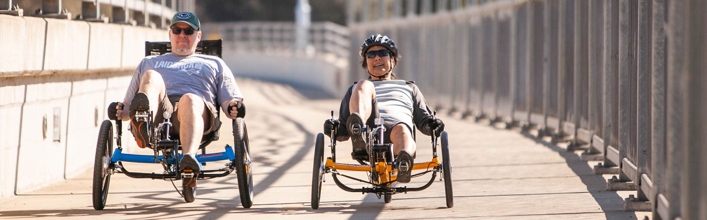 Two men riding Greenspeed recumbent trikes over the American River