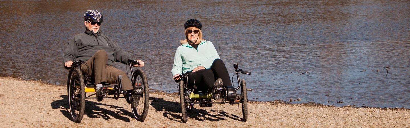 Older couple sitting on recumbent trikes on an American River riverbank