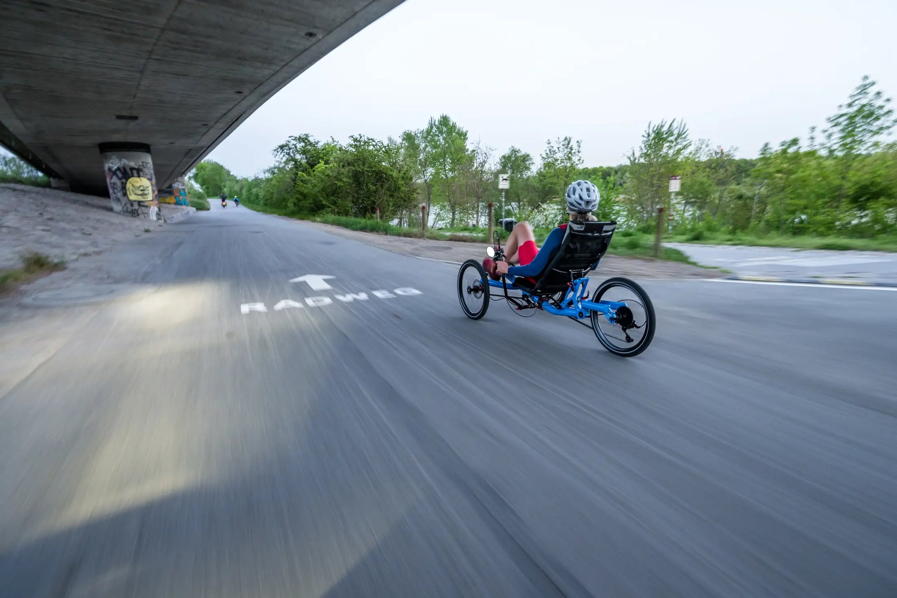 Rider on a blue AZUB TRIcon 20 recumbent trike cruising a paved cycle path