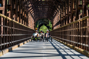 Riders on AZUB T-Tris 20 recumbent trikes on a wooded trail bridge