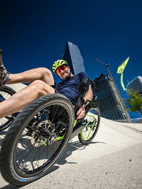 Rider cornering on an AZUB Ti-FLY 26 recumbent trike in the city