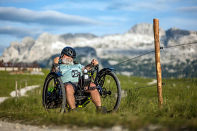 Rider on an AZUB Ti-FLY X on a mountain trail below snowy peaks