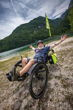 Rider stretching arms wide on an AZUB Ti-FLY X beside a mountain lake