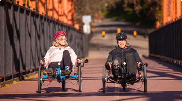 Smiling couple riding recumbent trikes across the Fair Oaks Bridge