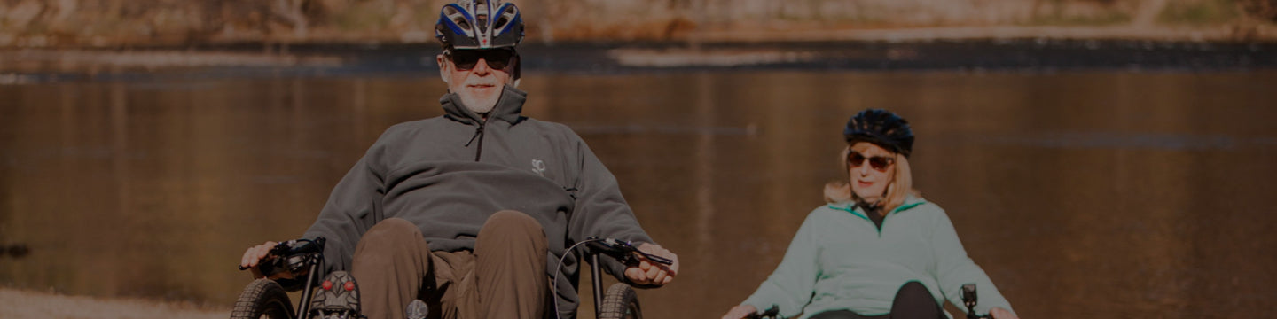 Older couple happily riding their recumbent trikes alongside the American River