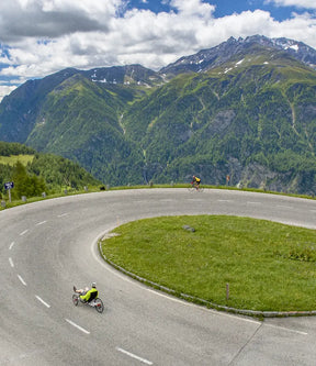 Rider on an AZUB TRIcon 26 recumbent trike descending an alpine mountain road