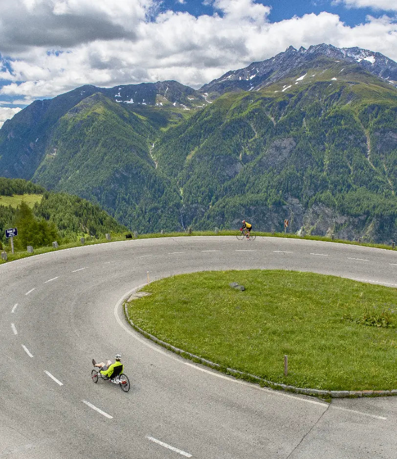 Rider on an AZUB TRIcon 26 recumbent trike descending an alpine mountain road