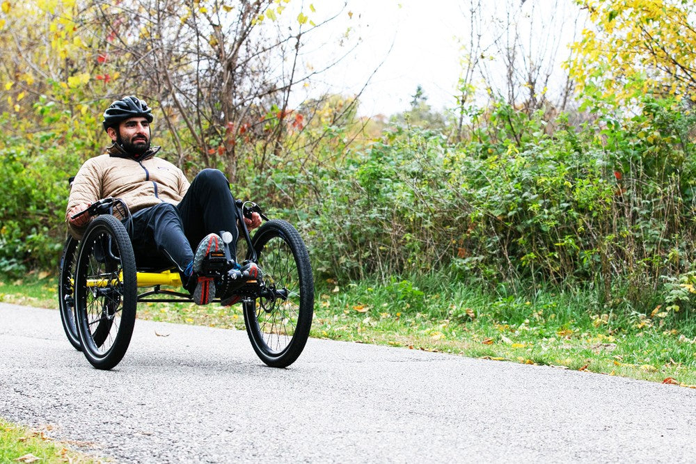 Man riding a TerraTrike Rambler recumbent trike on a paved path in fall