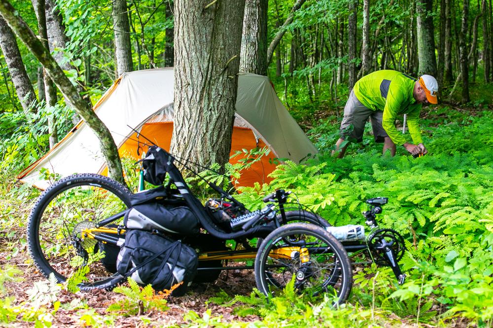 TerraTrike Gran Tourismo recumbent trike loaded for bikepacking at a forest campsite