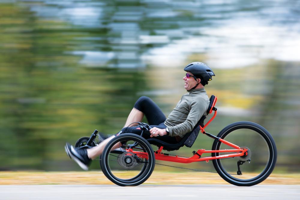 Rider in motion on a TerraTrike GTS recumbent trike on a wooded path