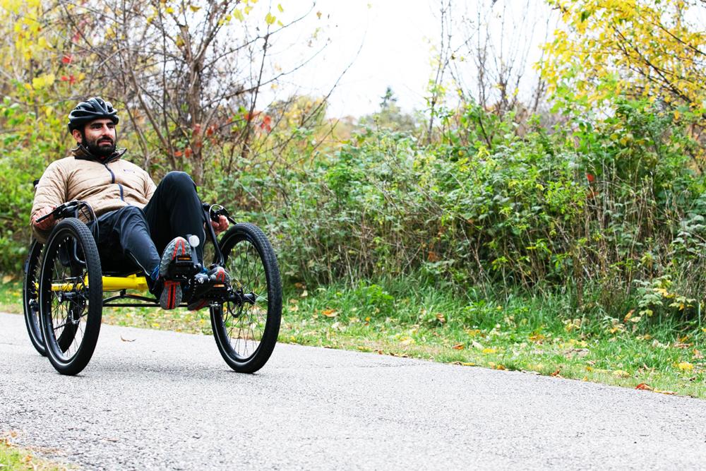 Rider on a TerraTrike Rambler recumbent trike on an autumn tree-lined path