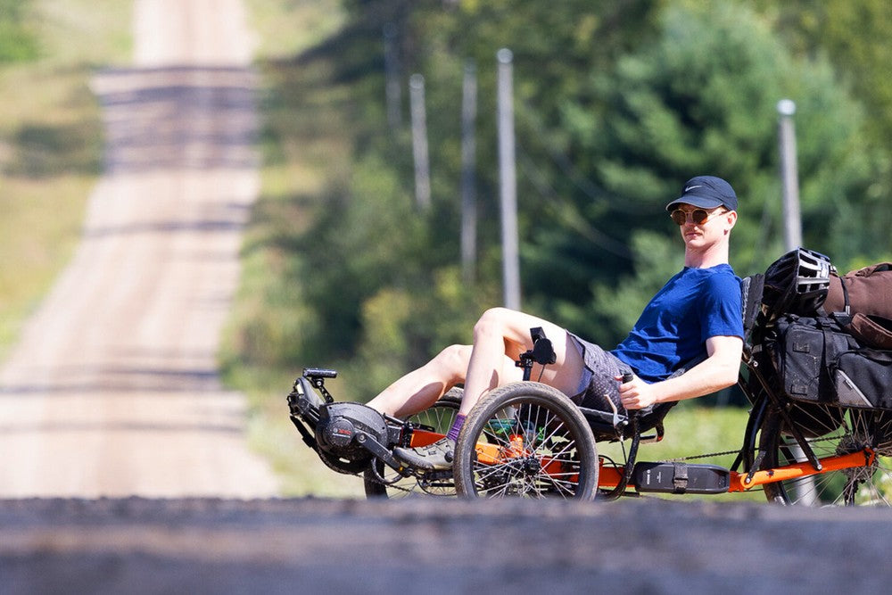 Rider on a loaded GreenSpeed recumbent trike on an open country road