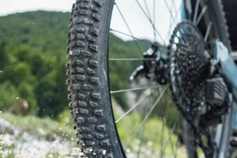 Rear 26-inch knobby wheel and cassette of an AZUB TRIcon GR trike on gravel