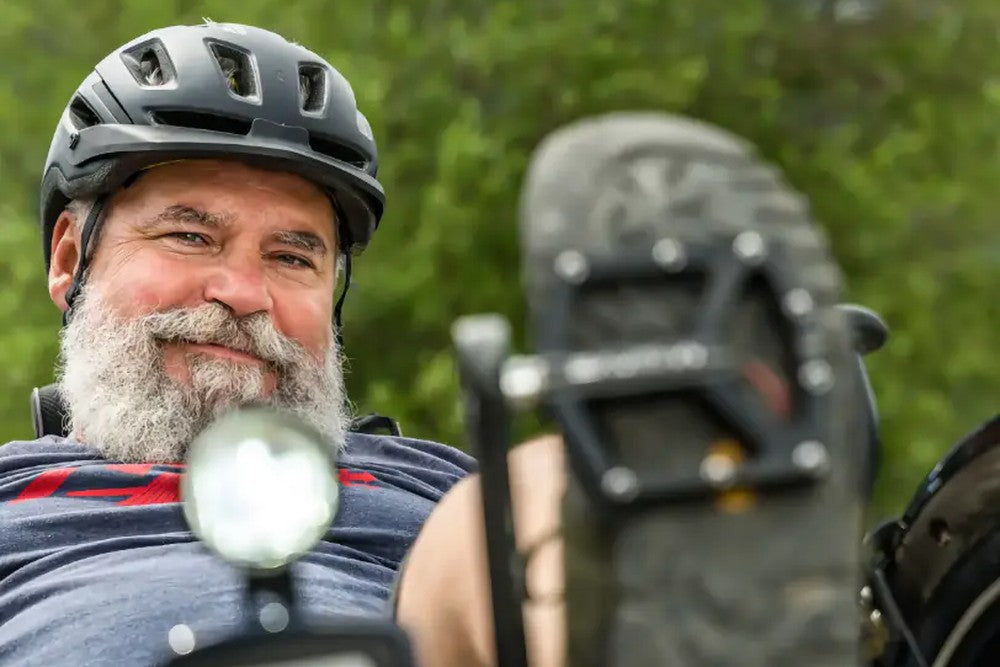 Smiling rider in a helmet riding an AZUB T-Tris AR recumbent trike outdoors