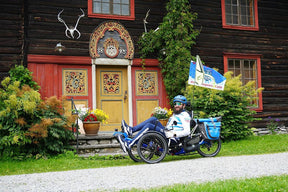 Rider seated on an AZUB Ti-FLY 20 recumbent trike outside a Norwegian house